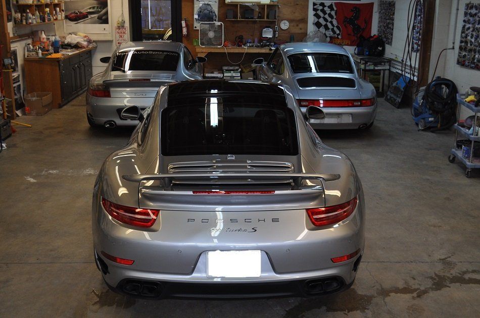 A silver porsche is parked in a garage with other cars